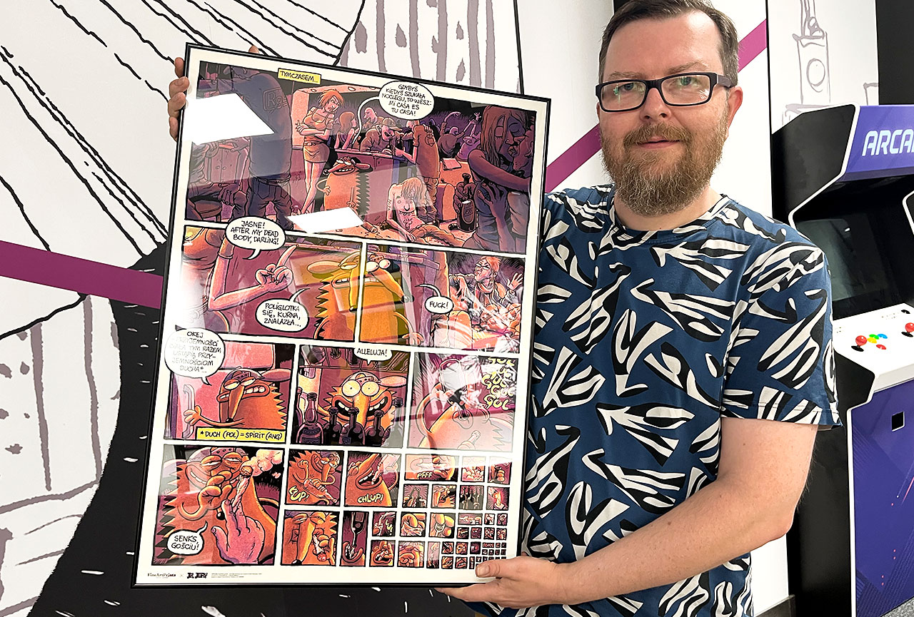 Tomasz Lew Leśniak trzyma plakat z planszą z komiksu Jeż Jerzy